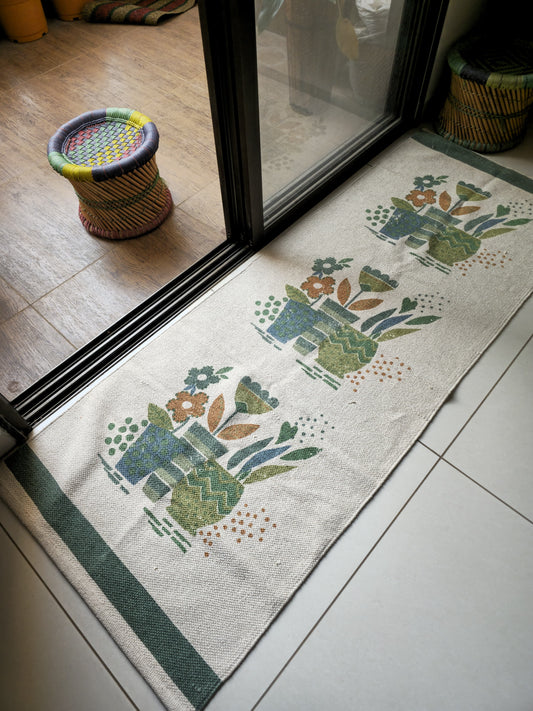 Chic cotton rug with flower pot pattern in cream and green, styled in a cozy bedroom as a bedside runner for a minimal aesthetic look
