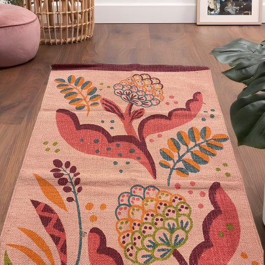 Cotton rug with modern leaf design in vibrant colors on peach base