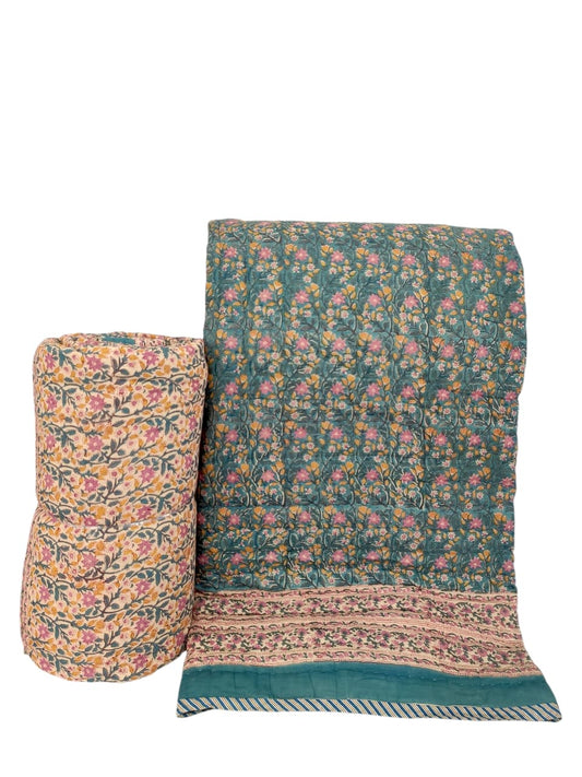 Floral patterned quilt and pillow on a white background