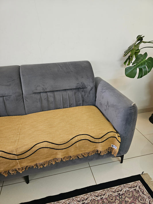 Gray sofa with a beige rug featuring black patterns on a tiled floor.