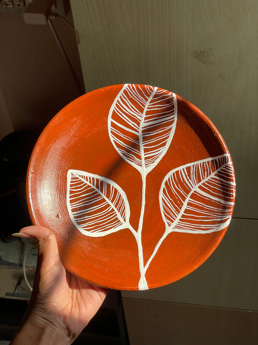 Decorative wall plates with leaf patterns in a home setting with plants and furniture.