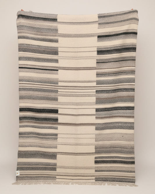 Striped blanket with blue and beige pattern draped over a surface.