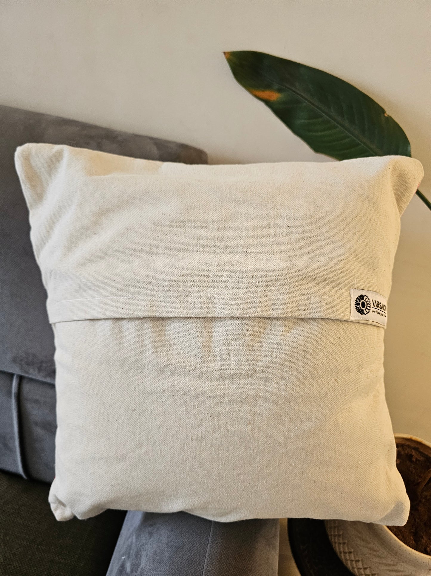 Beige pillow with a brand tag on a gray surface