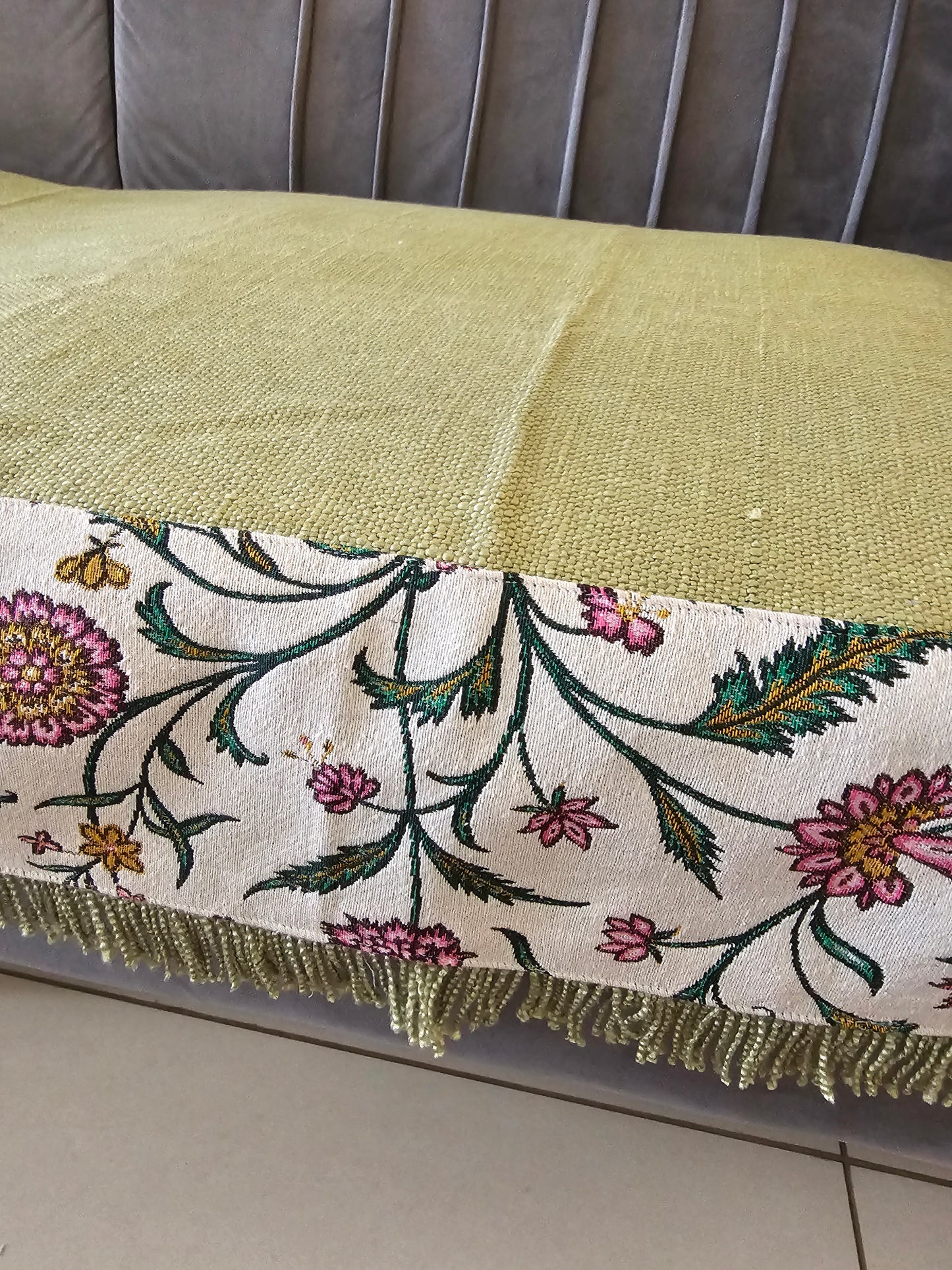 Decorative fabric with floral patterns and gold trim on a neutral background