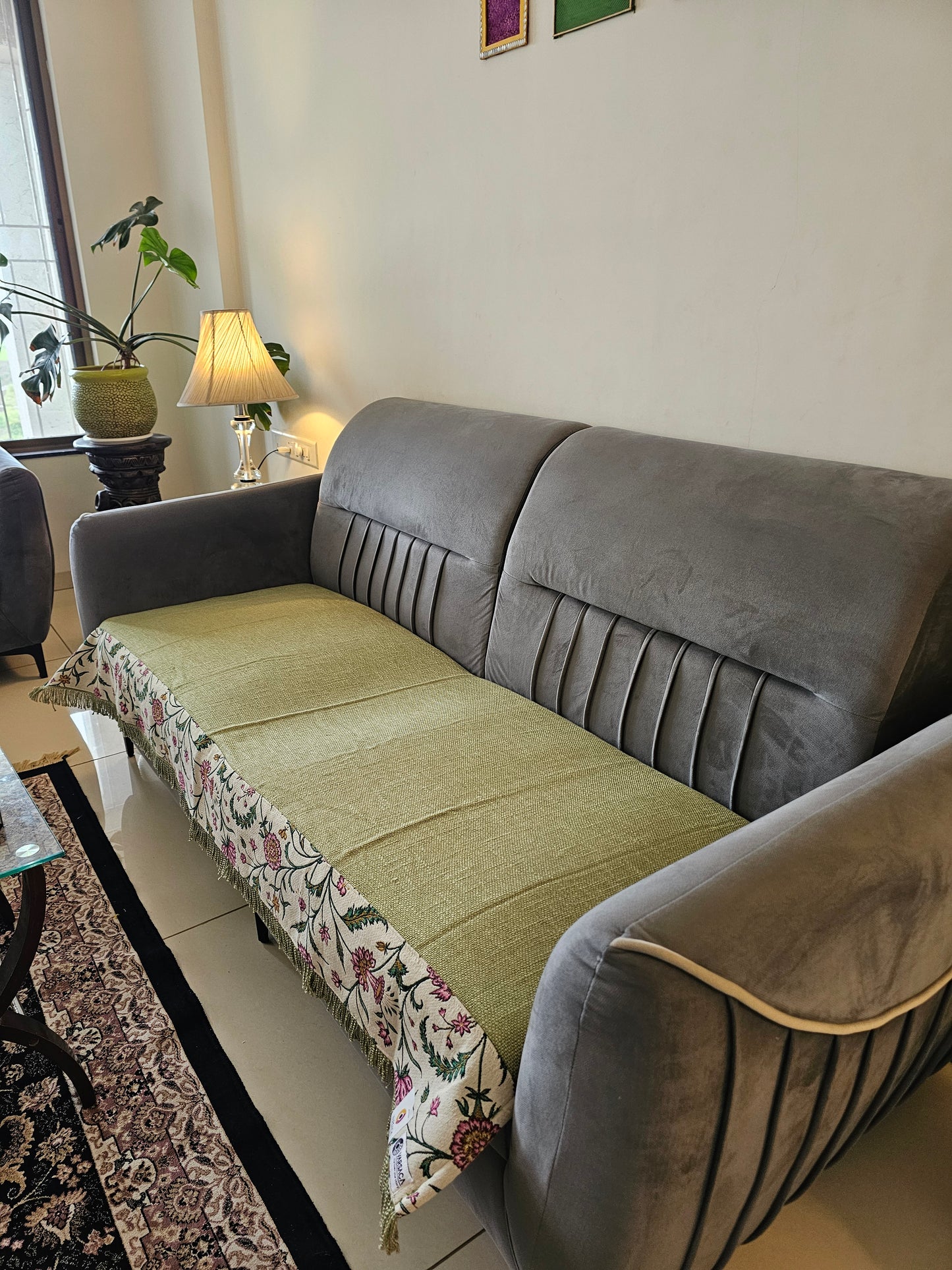 Gray sofa with a floral-patterned throw blanket in a living room setting.