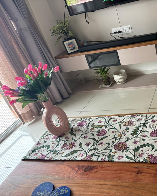 Living room with a floral rug on the floor, TV stand, and decorative items.