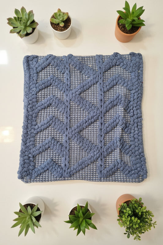Blue textured rug on a white surface with a person wearing red pants partially visible.