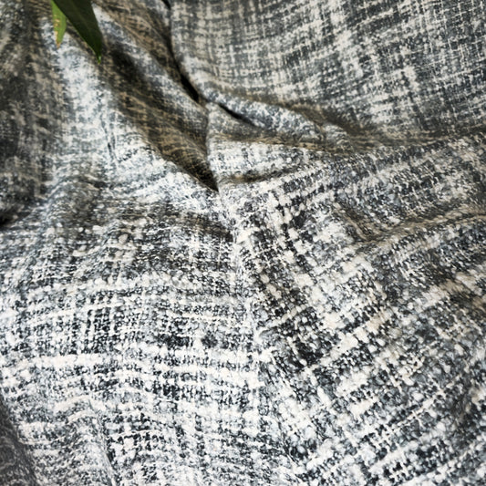 Close-up of a soft grey and white acrylic sofa throw with a handwoven design, showing texture and subtle blue tint.