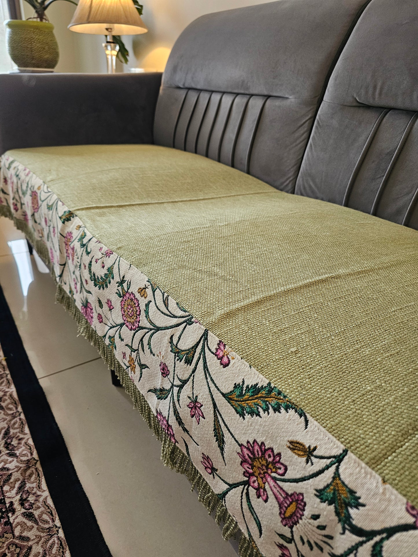 Close-up of a fabric with floral embroidery on a gray sofa.