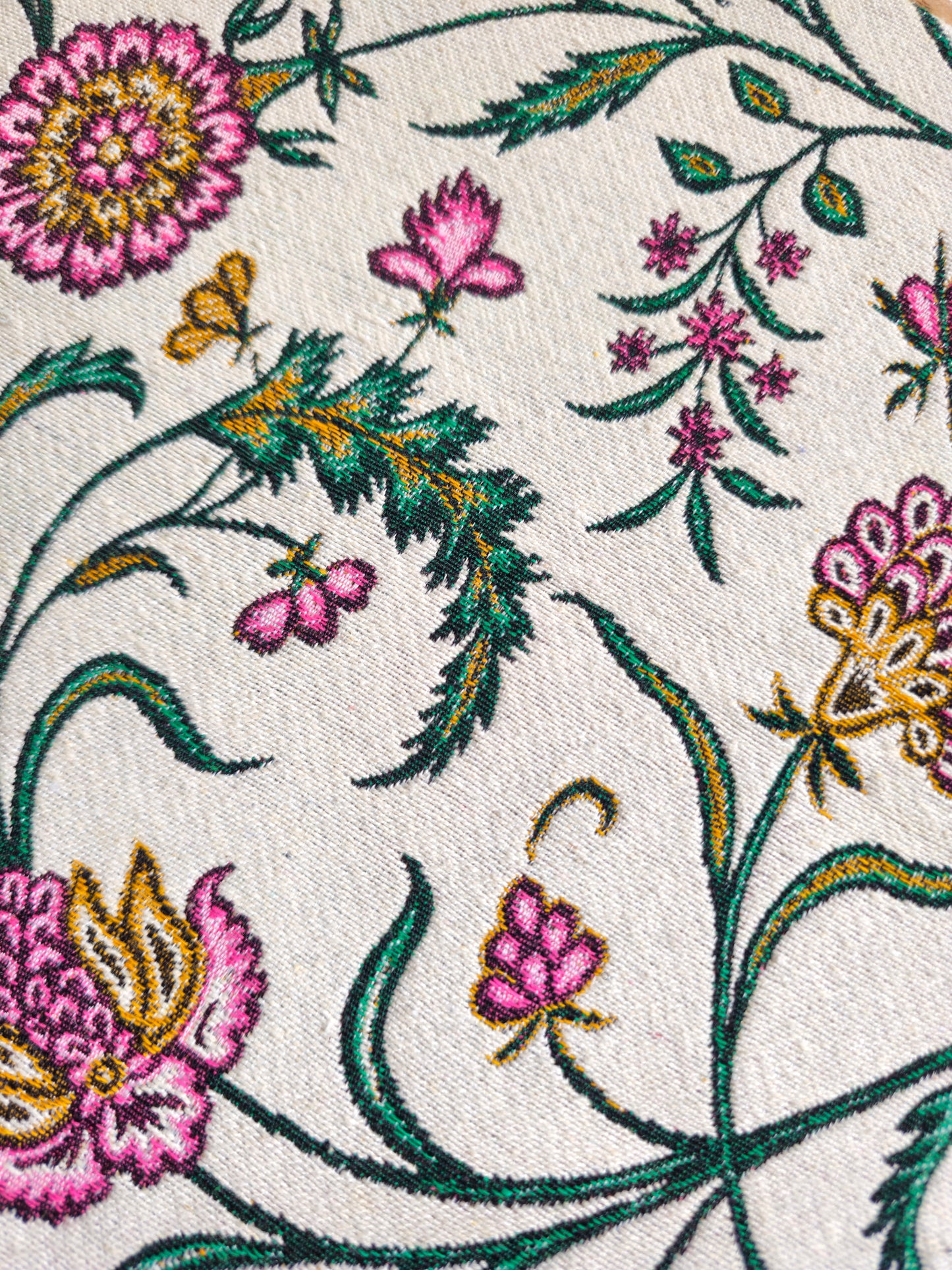 Close-up of floral embroidery with pink flowers and green leaves on a white background