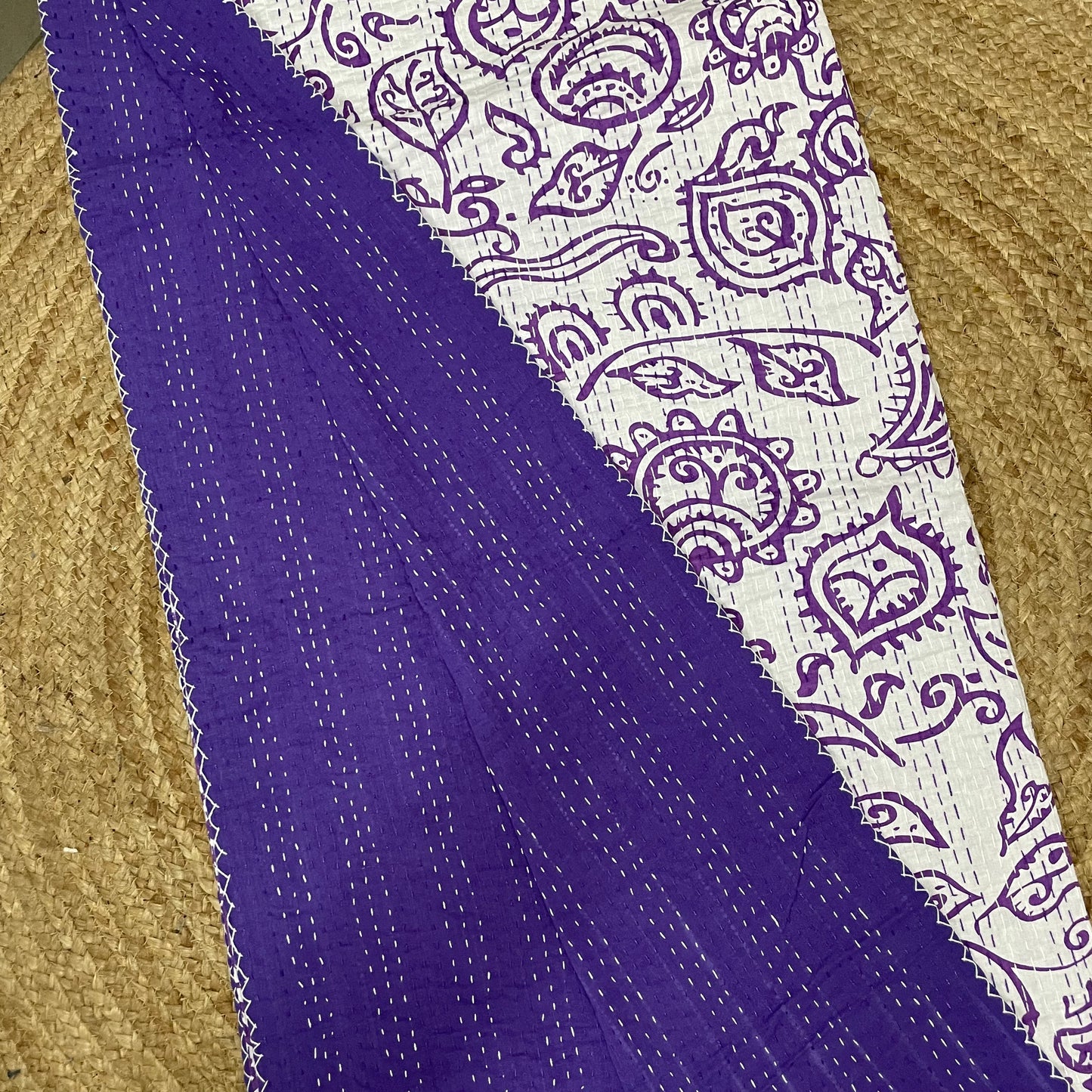Purple fabric with white paisley pattern on a textured surface