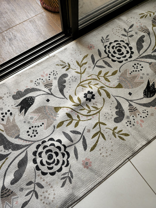 6x2.5 ft cream cotton rug with black and grey floral leafy abstract design laid flat in a minimal room