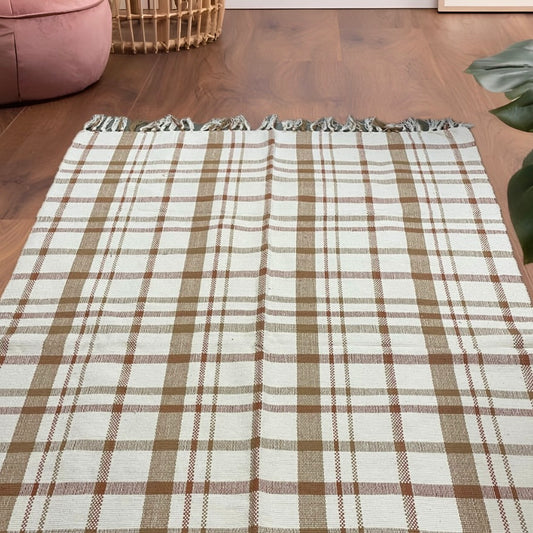 6x4 ft beige and rustic orange checquered handloom cotton dhurrie with tassels, styled in a boho-inspired living space
