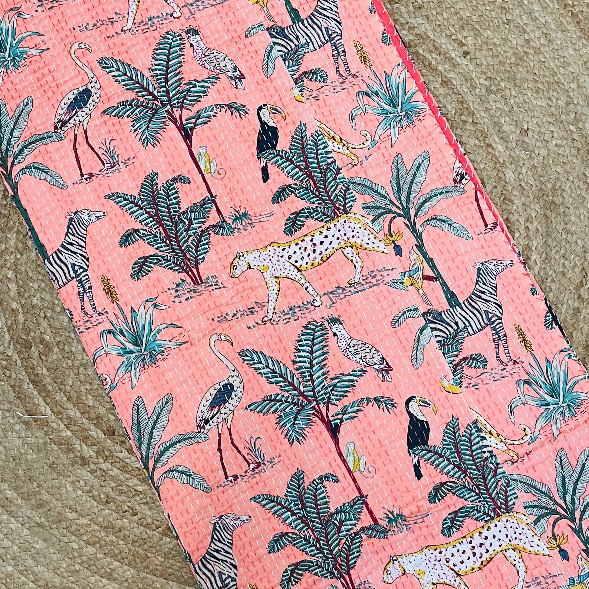 Fabric with a pink background featuring animal and plant patterns