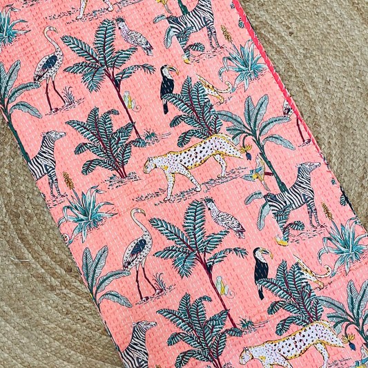 Fabric with a pink background featuring animal and plant patterns