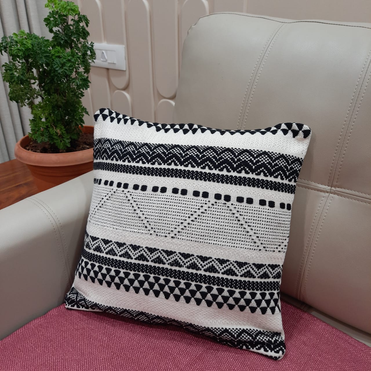 Artisanal rust and monochrome cushion set styled in a boho living room with plants and a woven rug.