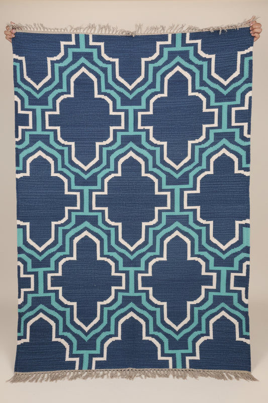 Blue and green patterned rug with white accents on a neutral background