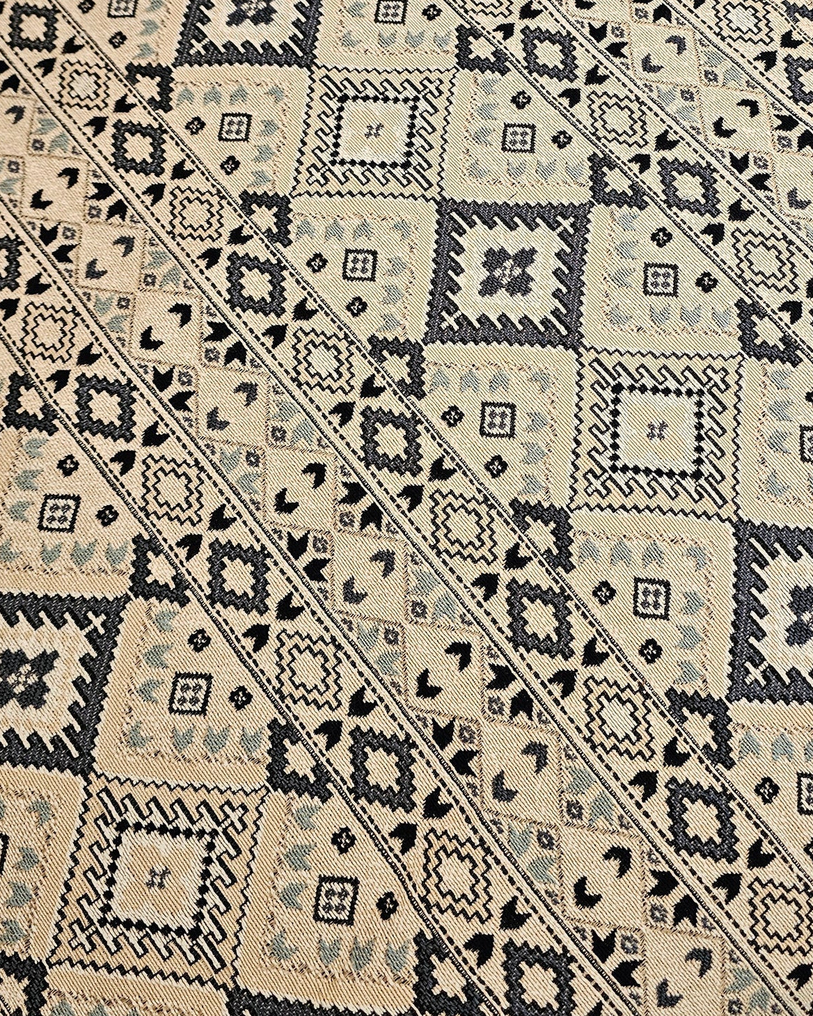 Close-up of a patterned rug with geometric design on a wooden floor.