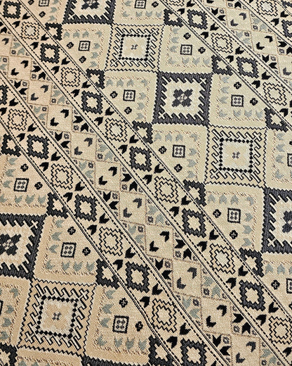 Close-up of a patterned rug with geometric design on a wooden floor.