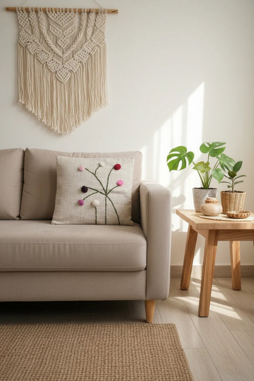 Close-up of the handcrafted 3D floral embroidery on a beige cotton cushion cover.