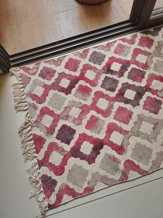 Cotton rug with hand-tied tassels and soft abstract watercolor pattern, styled beside a bed