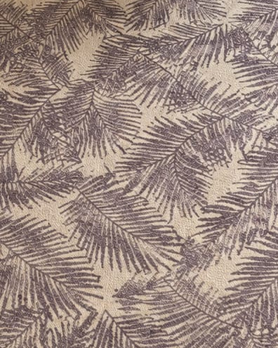 A full view of a muted purple and cream botanical leaf patterned flatweave cotton area rug styled in a modern living room with a light sofa and wooden coffee table.