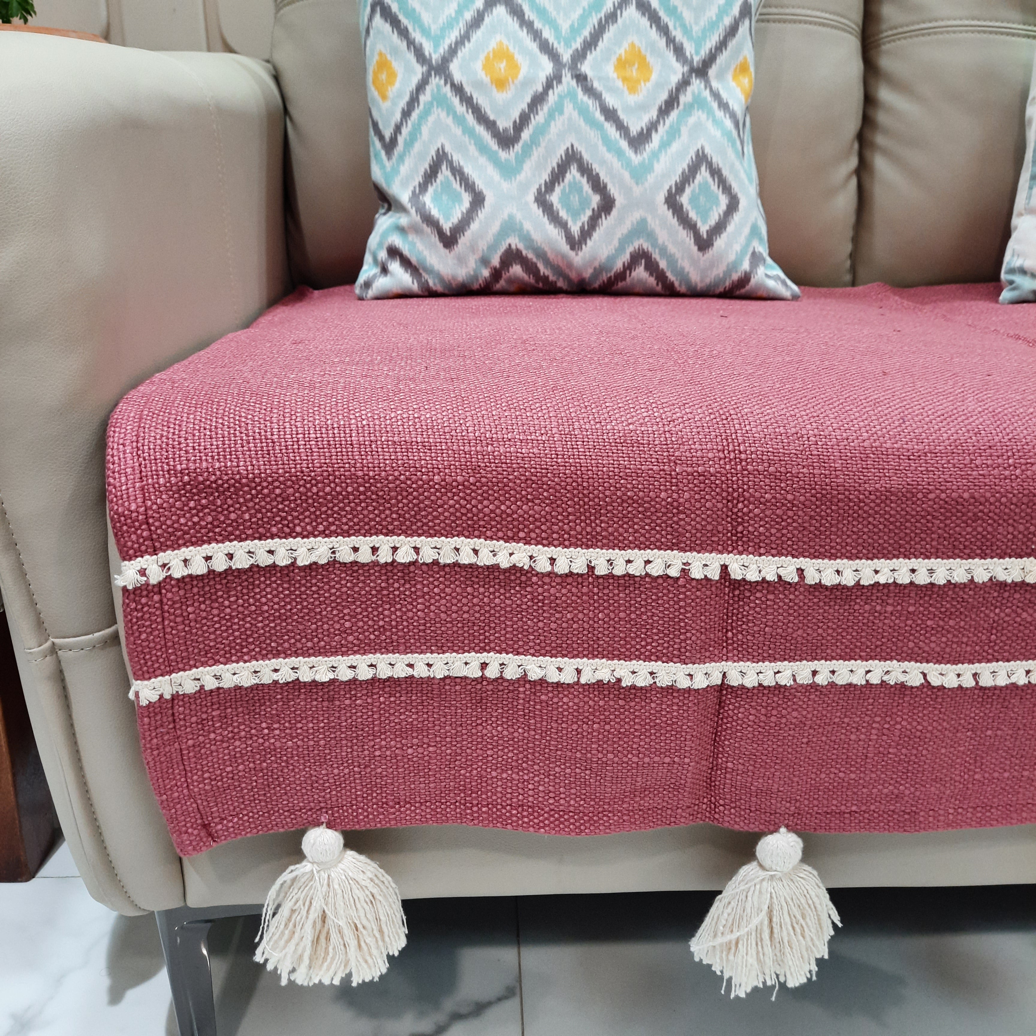 Decorative sofa cover in pink with tassel fringe