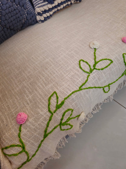 Embroidered fabric with green leaves and pink flowers on a beige background