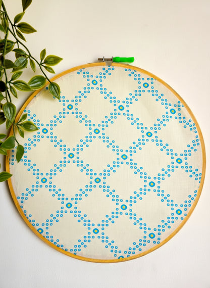 Embroidery hoop with blue and green pattern on a white background