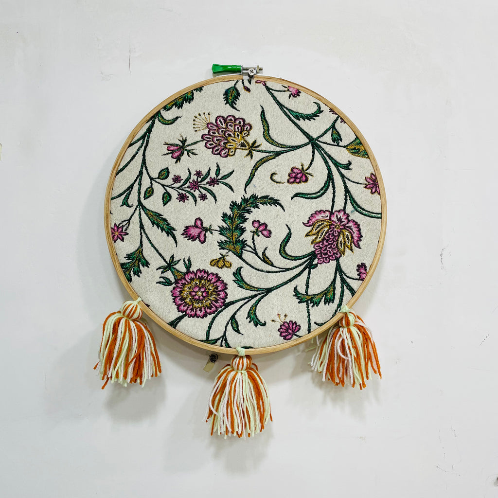 Embroidery hoop with floral pattern and tassels on a white background