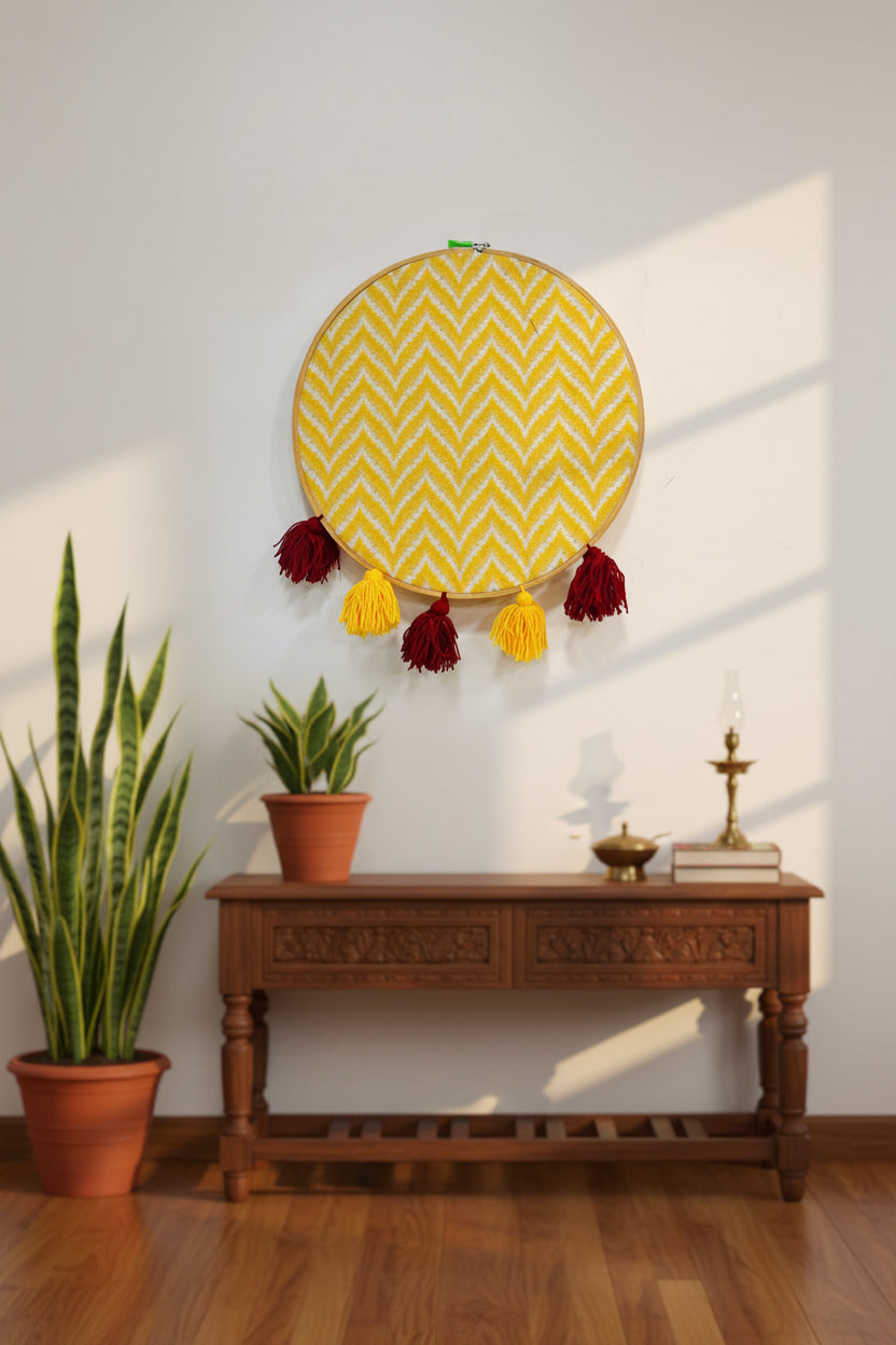Decorative wall hanging with yellow zigzag pattern and red tassels above a wooden console table.