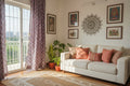 Living room with a white sofa, decorative pillows, plants, and a patterned rug.