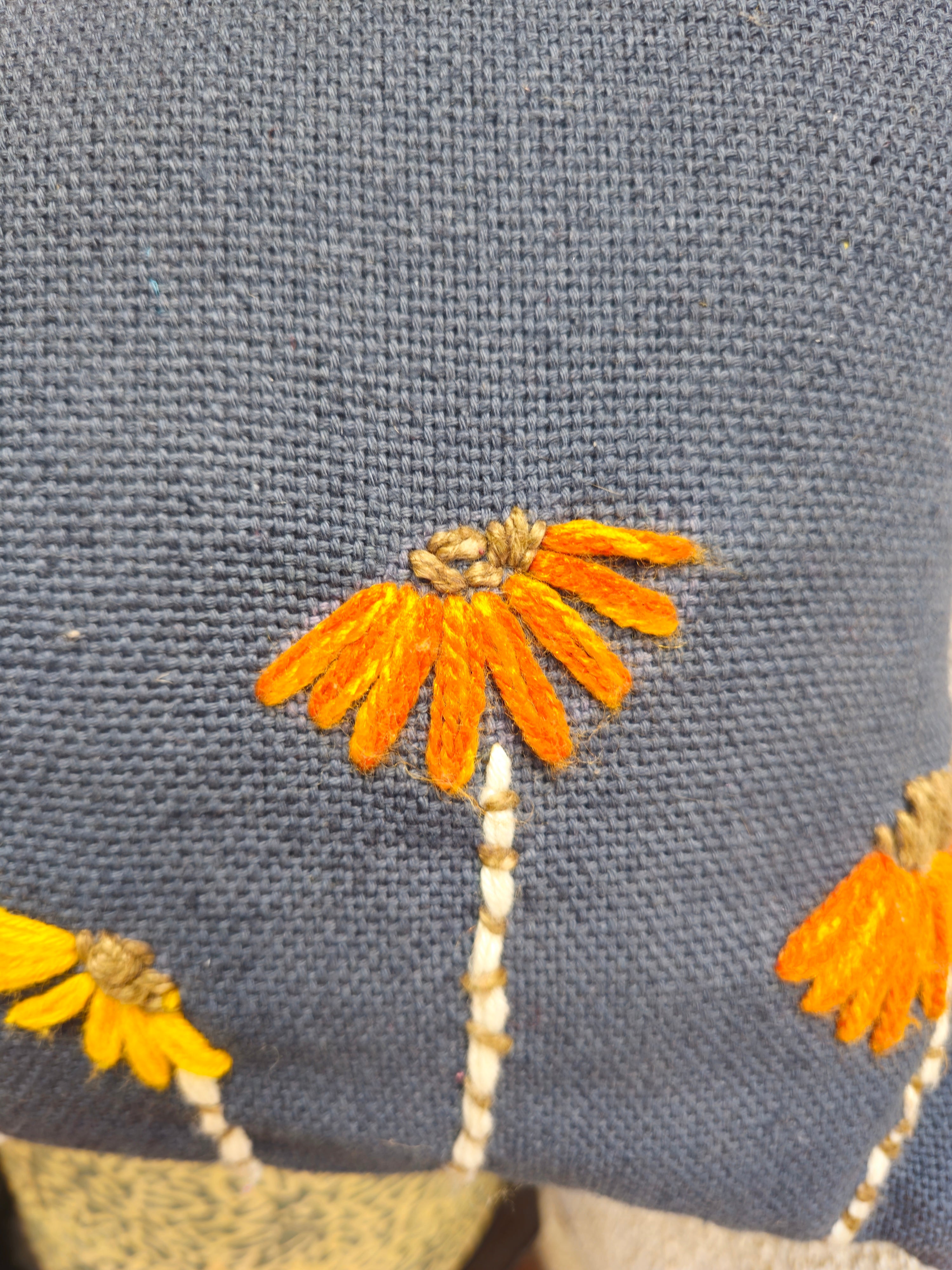 Embroidered orange and yellow flowers on a blue fabric background