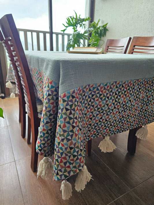 Patterned chair cover draped over a wooden chair with tassels, in a room with a window and plant.