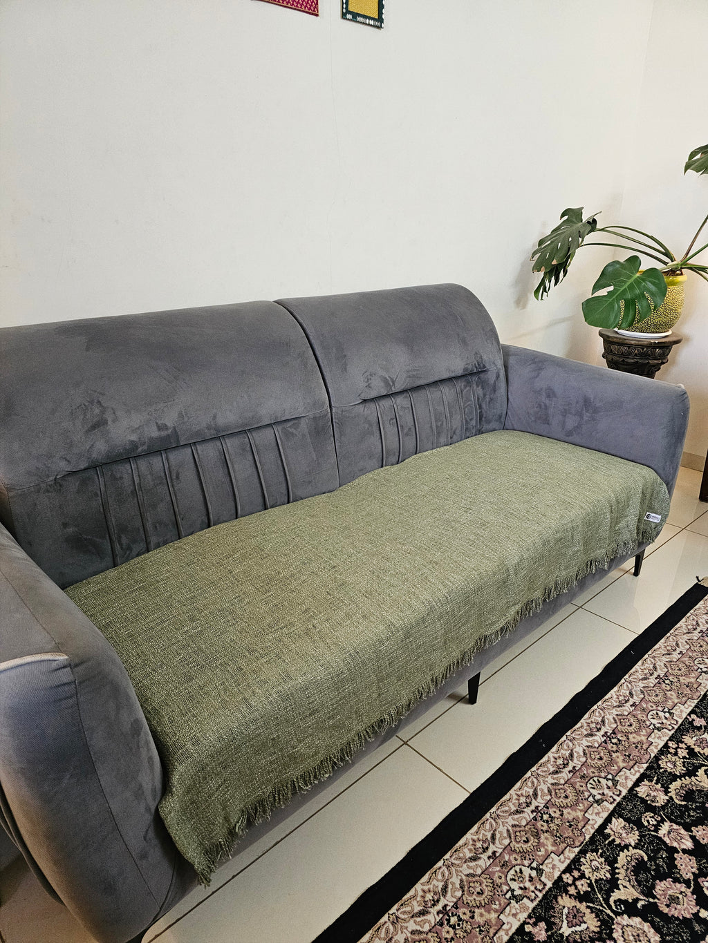 Gray sofa with a green blanket draped over it in a living room setting.