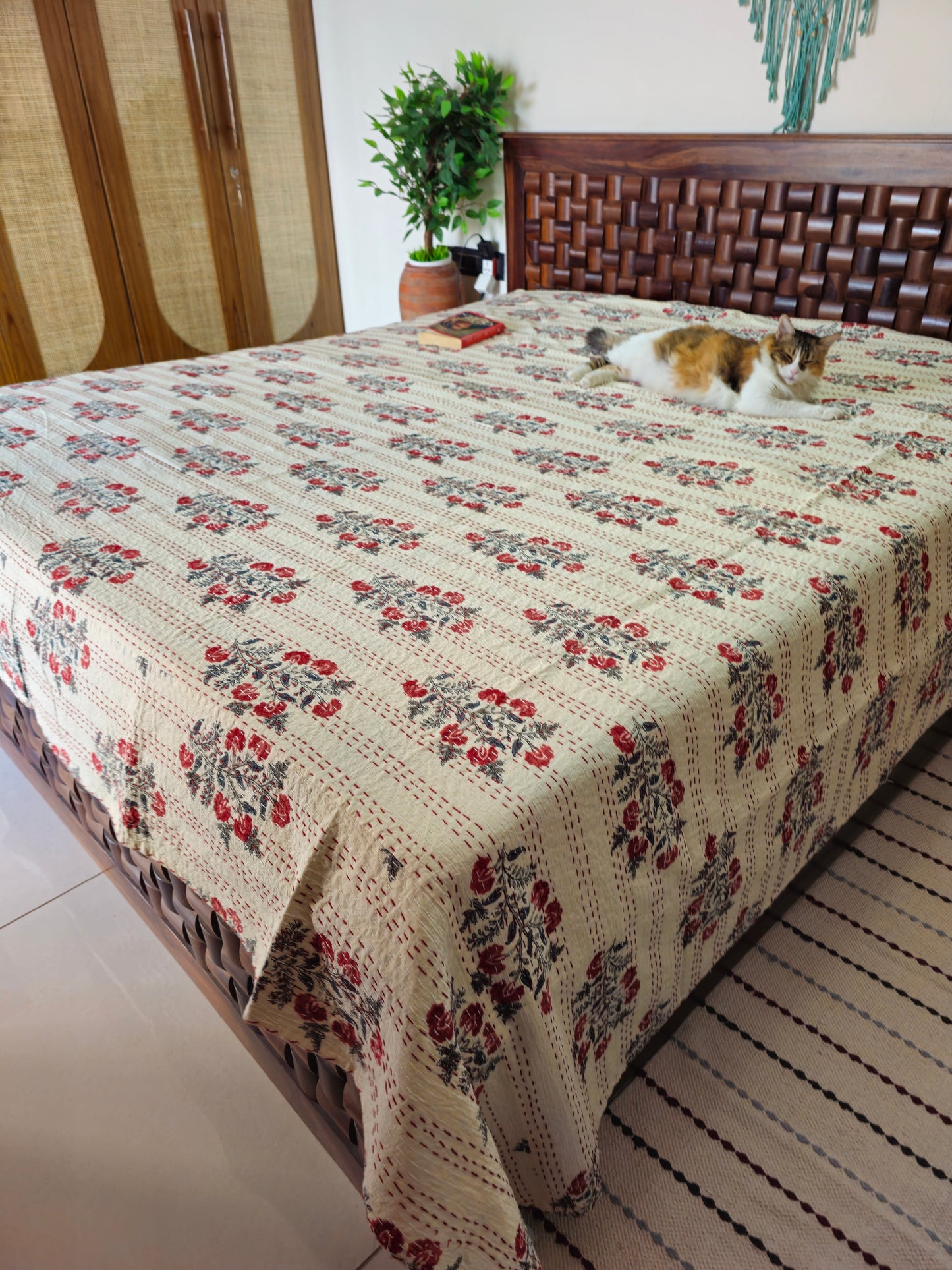 Floral-patterned quilt on a bed with a cat lying on it, in a room setting.