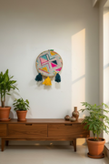 Embroidery hoop with colorful geometric pattern and tassels on a white background