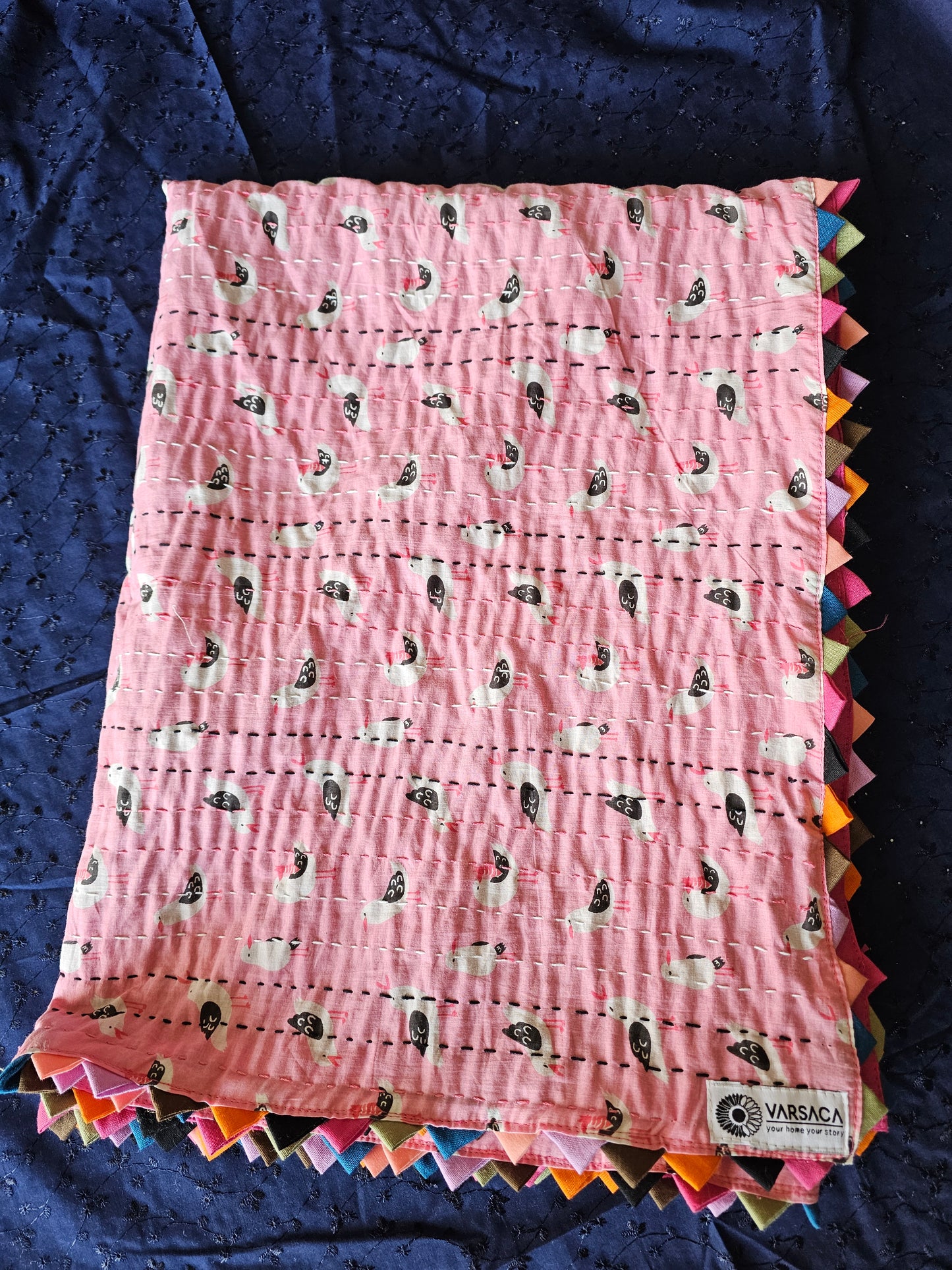 Baby wrapped in a pink blanket with animal pattern on a white surface