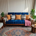 Set of 5 boho cushions with 3 rust orange threadwork covers and 2 black and white patterns on a wooden sofa.