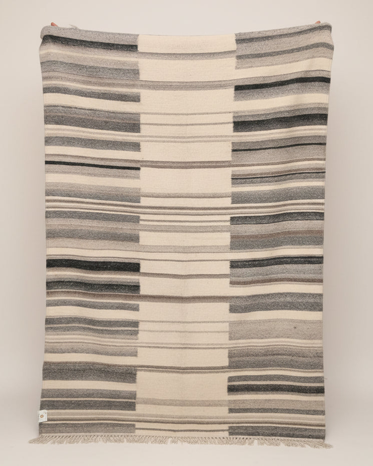 Striped blanket with blue and beige pattern draped over a surface.