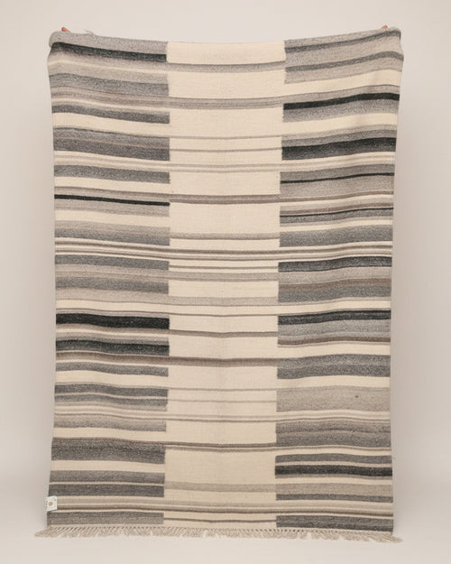 Striped blanket with blue and beige pattern draped over a surface.