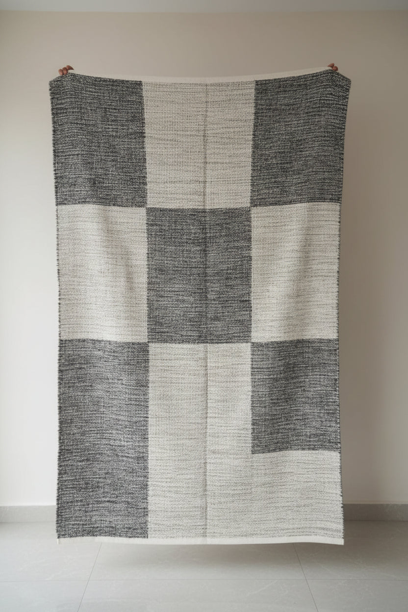 Textured blanket draped over a chair in a room with shelves and various items.