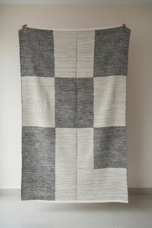 Textured blanket draped over a chair in a room with shelves and various items.