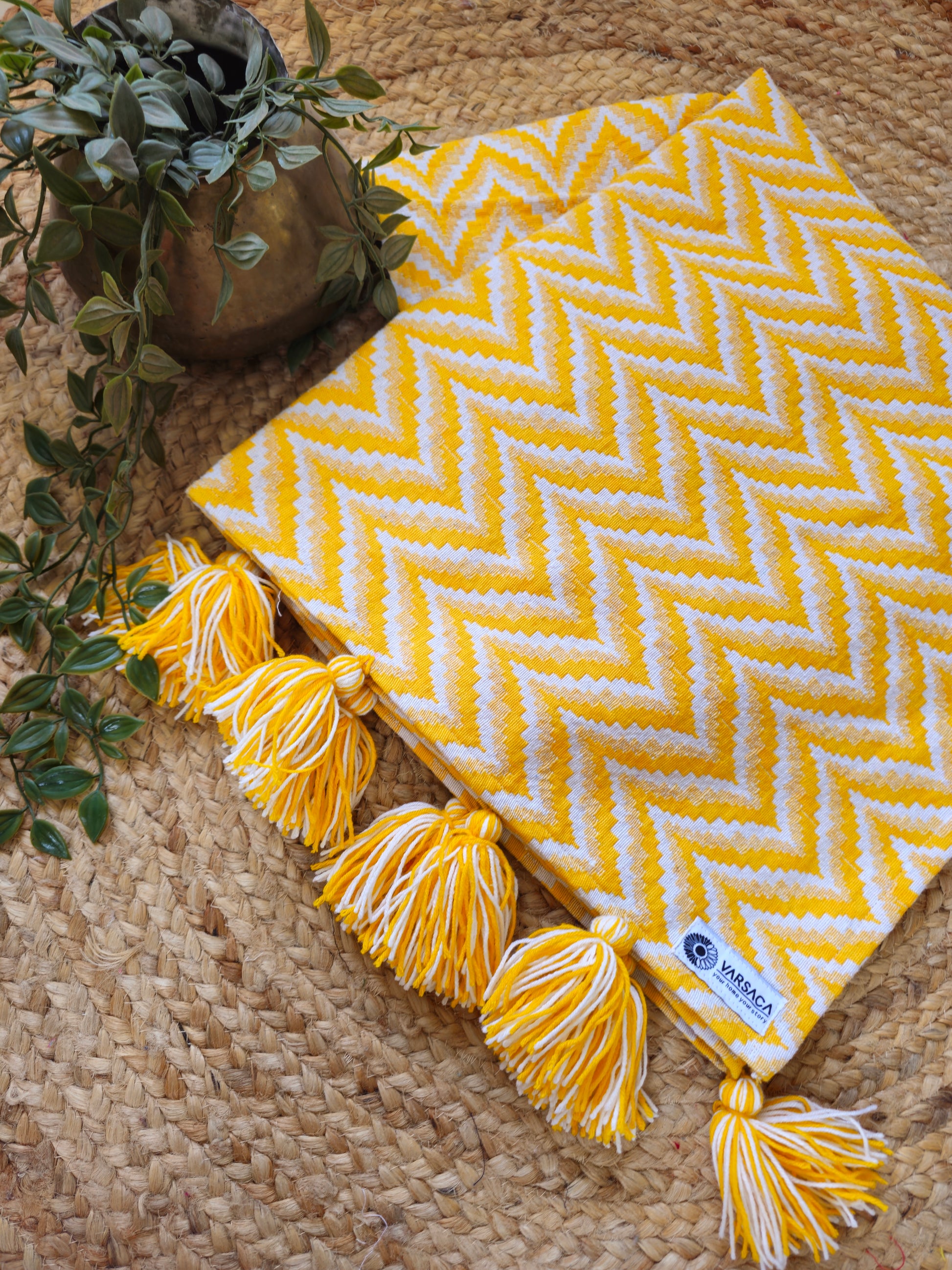 Yellow chevron blanket with tassels on a woven surface