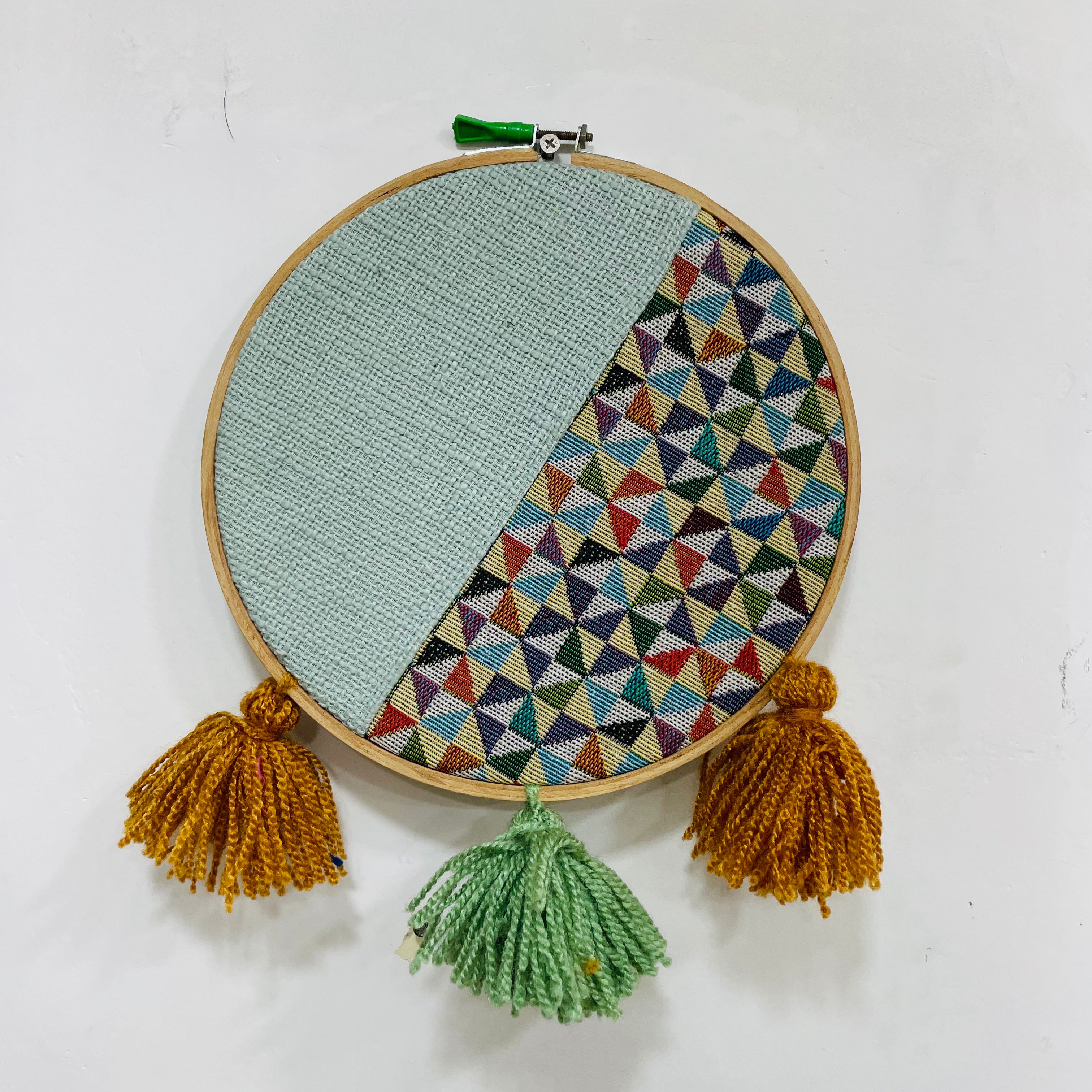 Embroidery hoop with geometric pattern and tassels on a white background