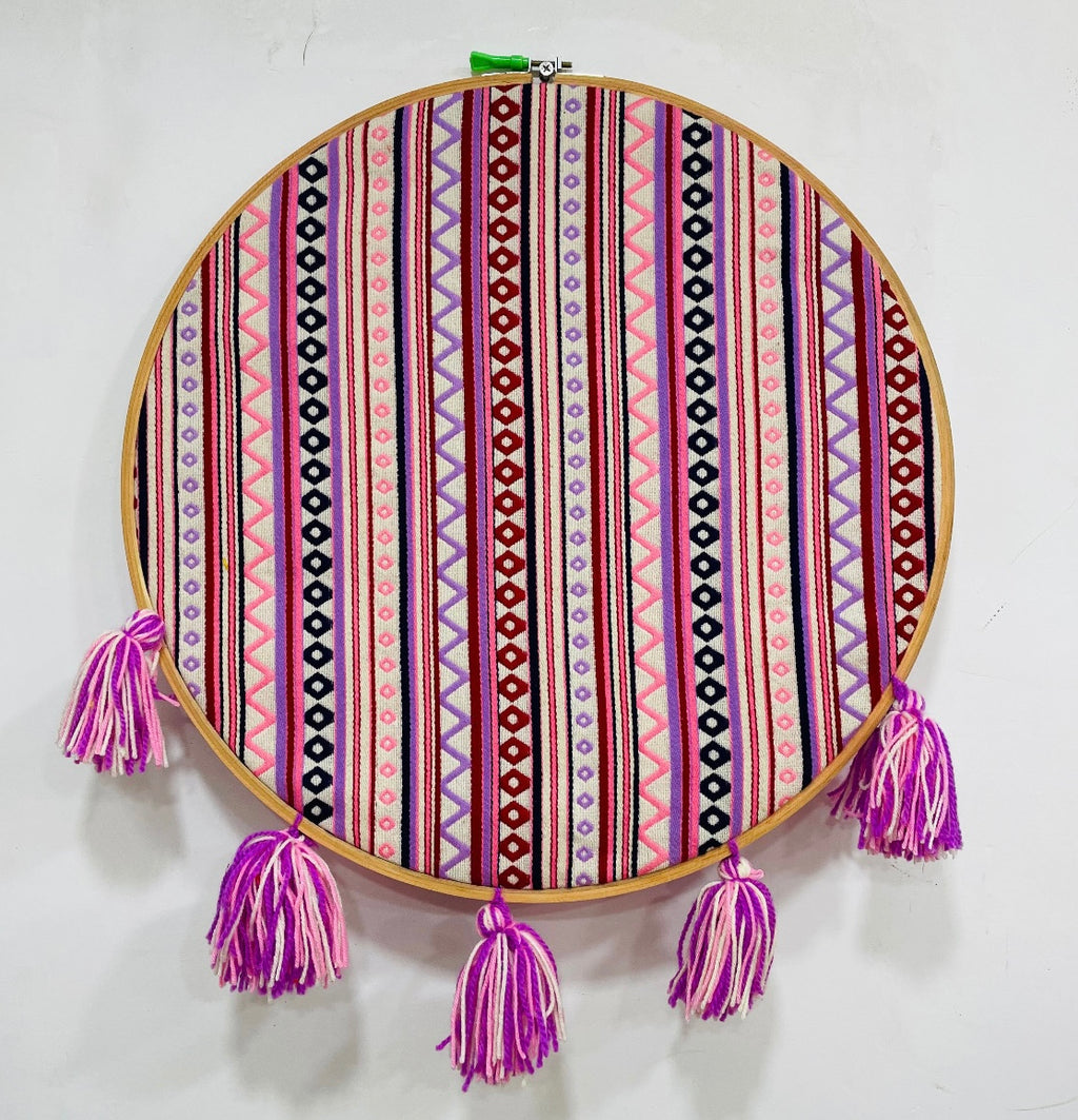Decorative hoop with colorful striped pattern and purple tassels on a white background