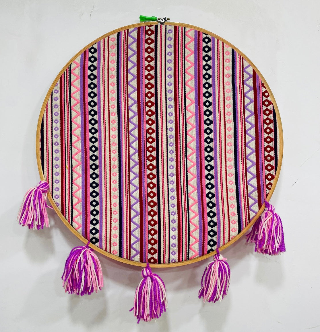 Decorative hoop with colorful striped pattern and purple tassels on a white background