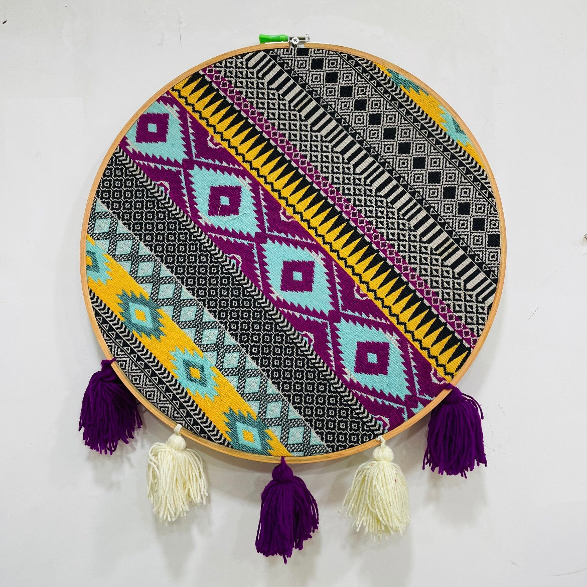 Decorative hoop with geometric pattern and tassels on a white background