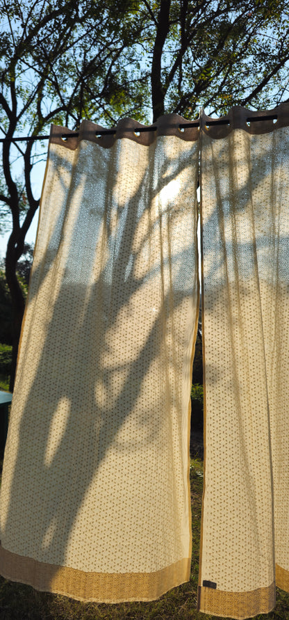 Beige curtains hanging outdoors with trees in the background
