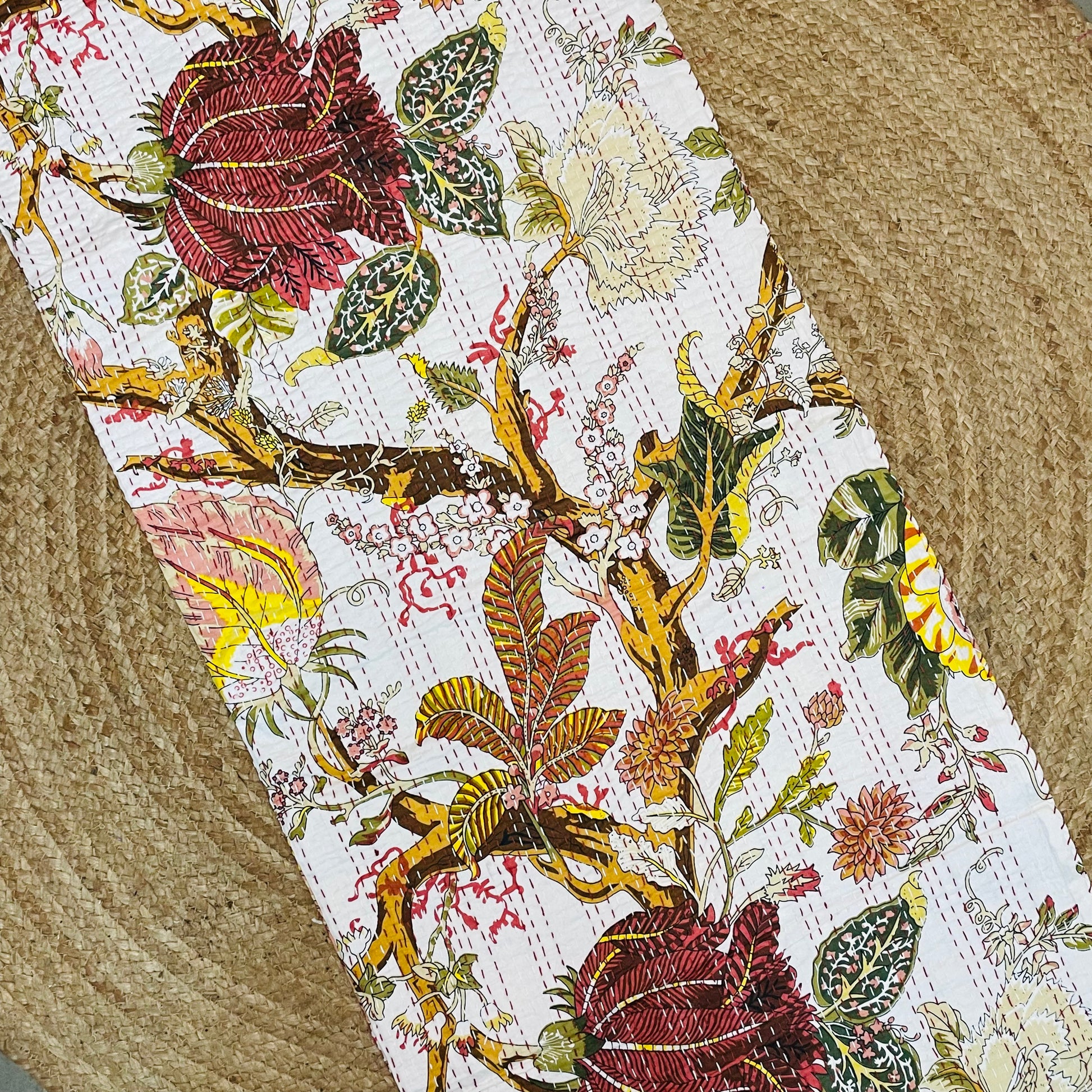 Close-up of a floral-patterned fabric with red roses and green leaves on a textured surface.